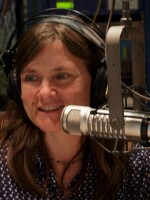 Headshot of a woman wearing headphones in front of a microphone