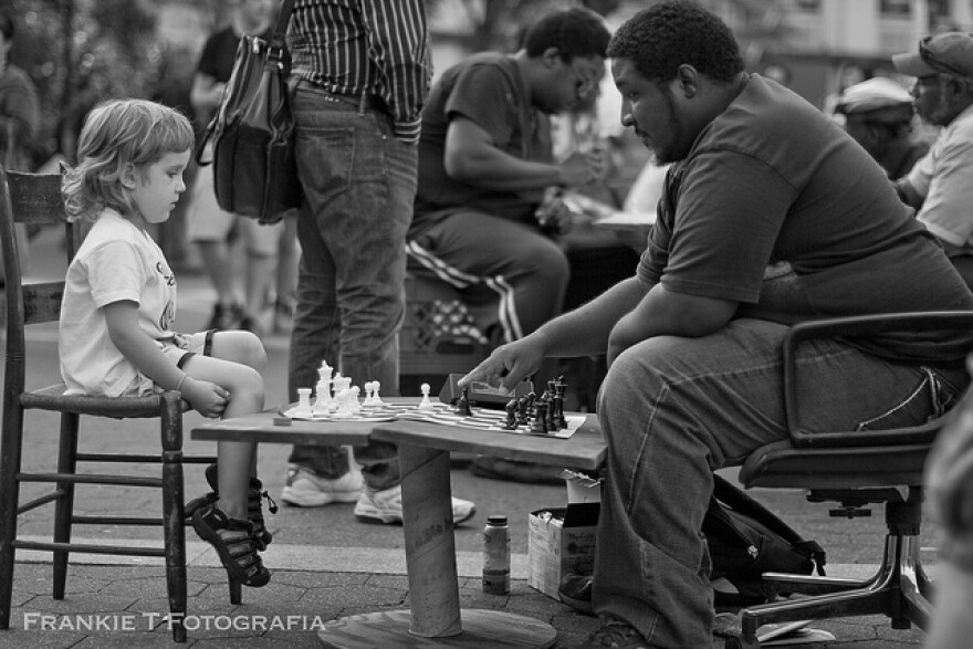 child and man playing chess outdoors