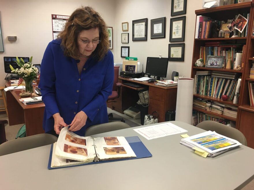 Christina Miller, director of the Millhopper Montessori School, flips through a photo album filled with students and school pictures from the early 1980s. (Kylie Widseth/WUFT News)