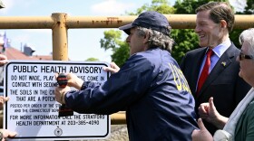 David Cash, New England Regional Administrator, EPA, along with Sen. Richard Blumenthal removing a sign advising passerby from entering the creek due to chemical contamination in Stratford, Connecticut on May 13, 2024. The creek is now deemed remediated even as other parts of the former Raymark industrial site continue to be cleaned up in a project that will last at least another four years.
