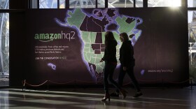 Amazon employees walk in front of a map highlighting 238 cities that submitted bids for Amazon's second headquarters in the lobby of the Day 1 building on Tuesday, October 24, 2017, in Seattle. 