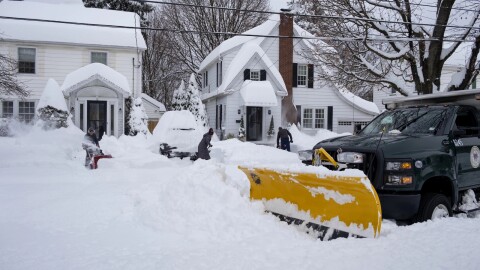 A snow removal truck awaits assistance after becoming stuck in the snow as residents work to clear sidewalks in Binghamton during a winter storm in 2020.