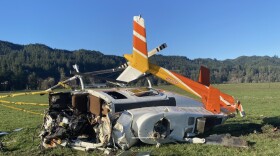 A crashed helicopter rests in a field
