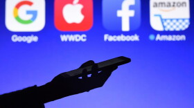 This photograph taken on Sept. 28, 2017, shows a smartphone being operated in front of logos for Google, Apple, Facebook and Amazon, in Hédé-Bazouges, western France. (Damien Meyer/AFP/Getty Images)