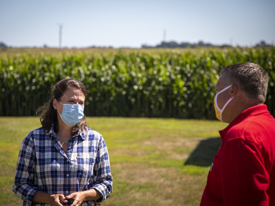 Democrat Theresa Greenfield, a real estate executive from Des Moines, talks with Trent Hatlen, who farms and raises hogs near Rembrandt, Iowa, on Aug. 11, 2020.