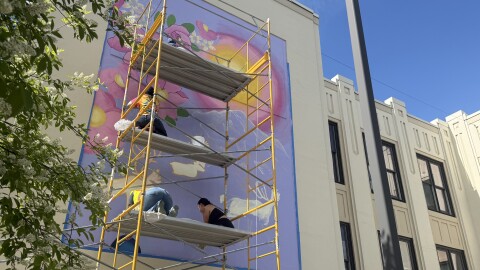 Artists and volunteers work on one of two murals slated for the facade of Fairbanks City Hall on June 7, 2026.