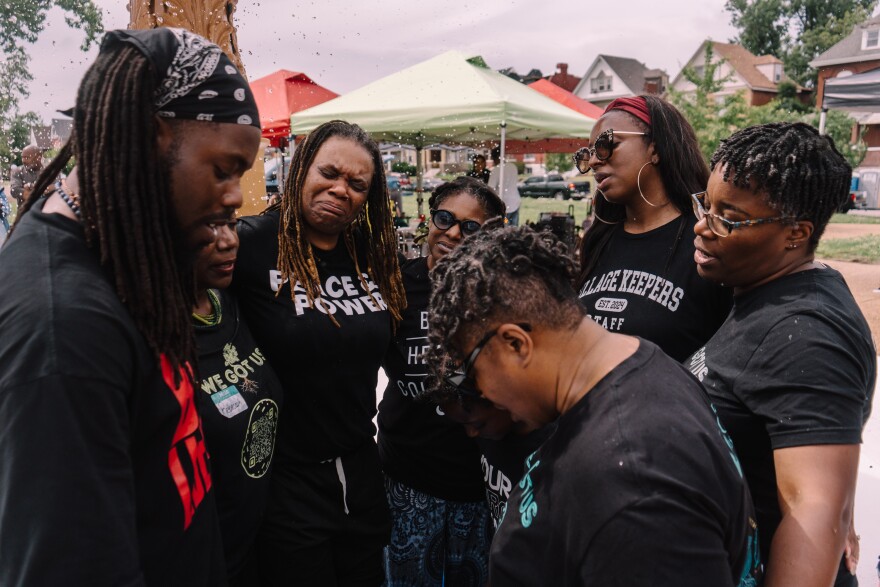 Members of the Black Healers Collective gather hands while in a pool of water to sing "Wade in the Water" on the first anniversary of the devastating May 2025 tornado at Fountain Park on Saturday in north St. Louis.