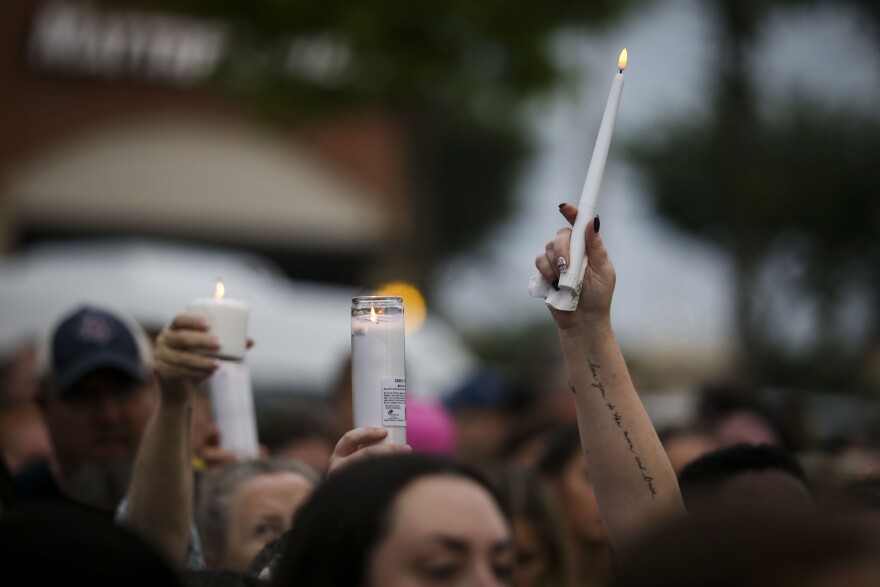 Community members hold up their candles during a vigil at the memorial for the victims of Saturday’s shooting Wednesday, May 10, 2023, at Allen Premium Outlets in Allen. 