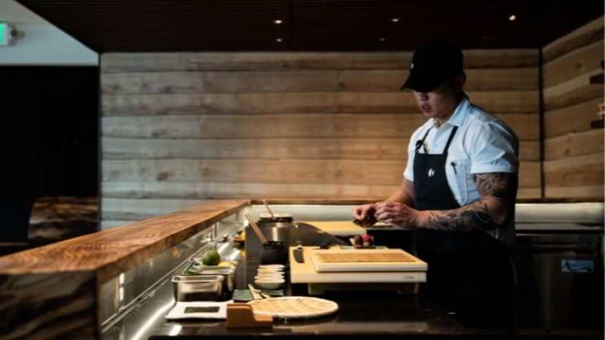 A sushi chef prepares food at a small sushi bar.