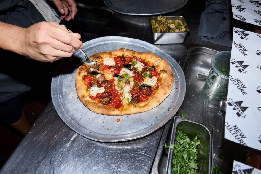 A person dressing a pizza.