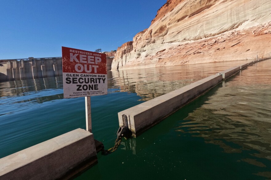 FILE - A sign reading "keep out" is displayed just upstream of Glen Canyon Dam at Lake Powell, June 8, 2022, in Page, Ariz.