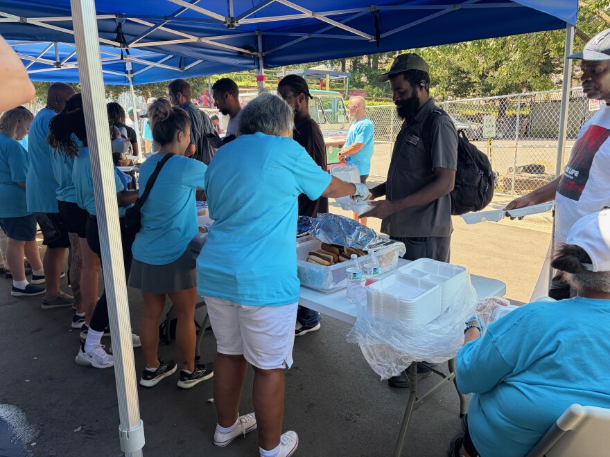 Volunteers serve lunch outside at the Roof Above Day Center. 