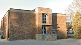 A two-story brick building with stairs to an elevated entrance and a sign at the top that reads 'Eugene Field School'