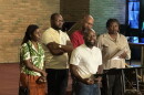 Five Haitians standing around a podium in a church. Haitian members of Organizing Undivided thank the Miami Valley community for publicly supporting Haitian immigrants.