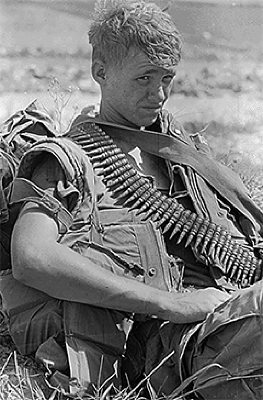 black-and-white photograph of a U.S. Marine during the Vietnam War. It shows a Marine taking a break from a ground movement.