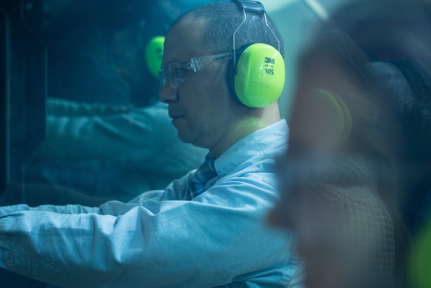 Dr. Erik Wallace, seen through bulletproof glass, shoots on the range. Wallace leads a discussion for all graduating medical students at the University of Colorado each year about firearm risk reduction and how to counsel patients on safe storage practices.