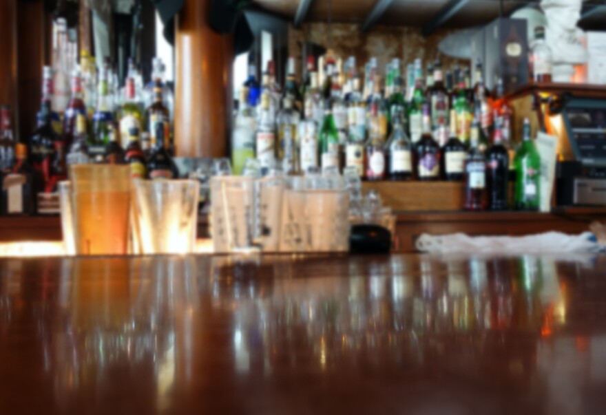 Blurred interior of a restaurant with liquor bottles in the background and empty bar in the foreground