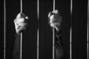 Hands holding a bar of prison