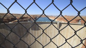 This Aug. 21, 2019 image shows Glen Canyon Dam beyond a chainlink fence near Page, Arizona.