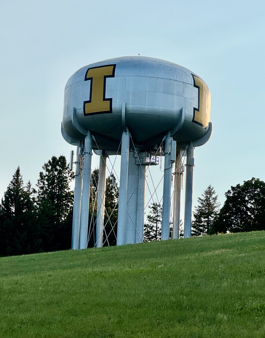 The University of Idaho's water tower stands on patch of green grass with a blue sky in the background.