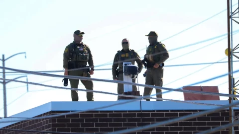Three men in Customs and Border Protection uniforms stand on the roof of the Broadview immigration facility taking pictures of the surrounding area on Oct. 9.