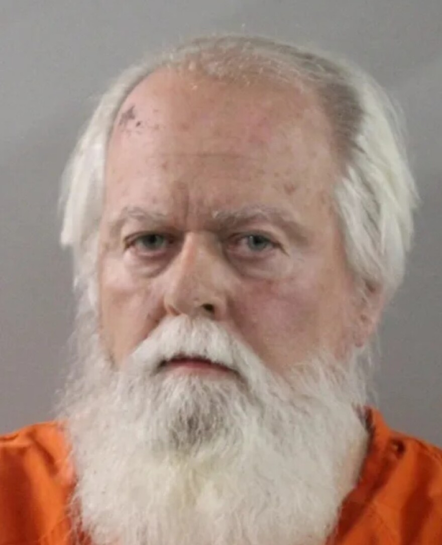 Old man with white hair and beard in orange jumpsuit
