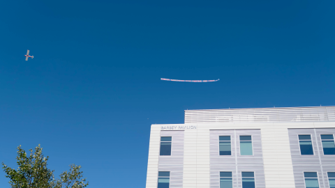 A biplane tows a banner over Cape Cod Hospital in Hyannis with the message "Cancer Awareness. Stay Positive And Fight."