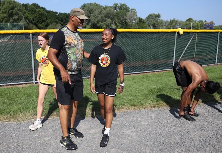 Mitchell Harris, left, talks with Loren Green during the Hoop N’ Holla summer basketball camp in Rochester. Harris and other coaches work with young athletes like Green and their families throughout the year, focusing not only on basketball skills and academics but also on helping players navigate the business of youth basketball and the opportunities and challenges that can come with success.