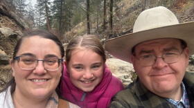 Tara Benson, Grace Benson and Jake Benson are framed together in a family photo with a mountainous background with green trees. 