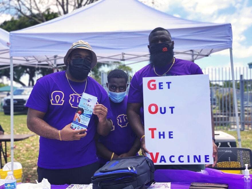 Members of Omega Psi Phi fraternity hold signs encouraging vaccination