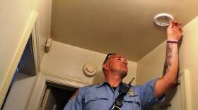 Indianapolis firefighter Derek Huff installs a smoke detector in a home on North Sherman Drive Tuesday.