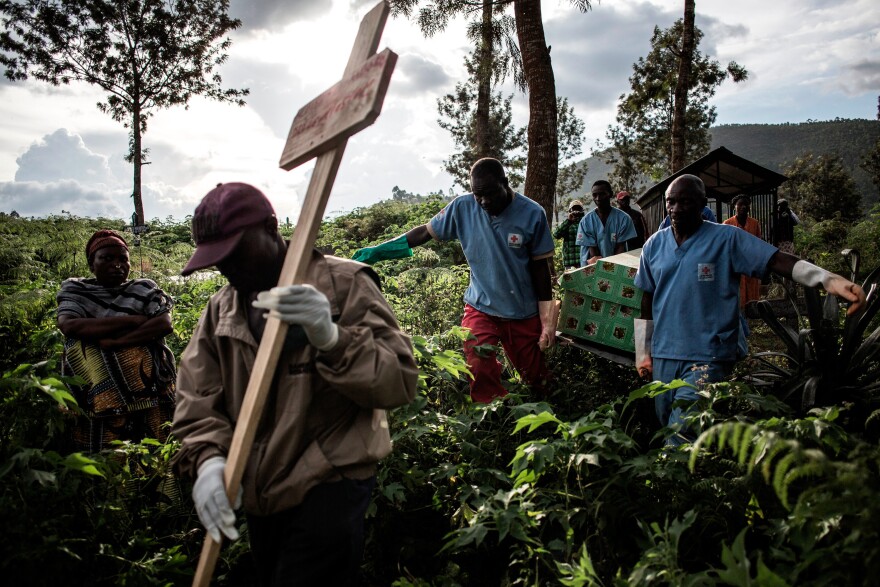 Health workers carry the coffins to the burial site.