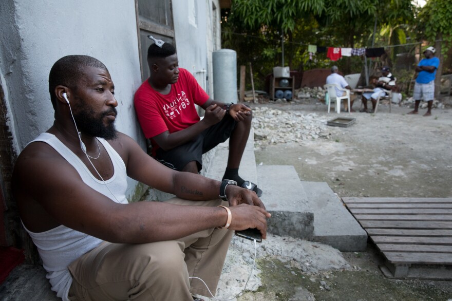 Odne Laguerre (left) and evacuee Bobson Timothee pass the time while other evacuees play cards at the Laguerre home.