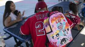 Josue Mosqueda wears her daughter's backpack while waiting for her classroom to open on the first day back to school at Sunkist Elementary School in Anaheim, Calif., Thursday, Aug. 11, 2022. (AP Photo/Jae C. Hong)