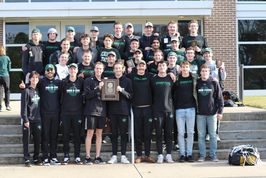 The men’s water polo team taking a group photo with their national championship trophy.