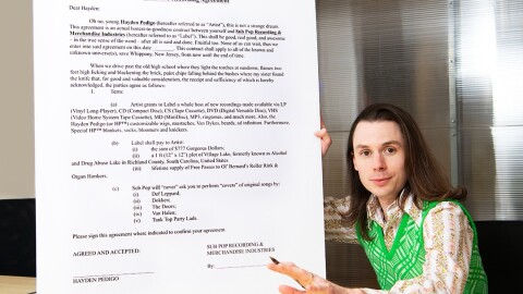 Hayden Pedigo poses with a comically large recording contract with Sub Pop Records.