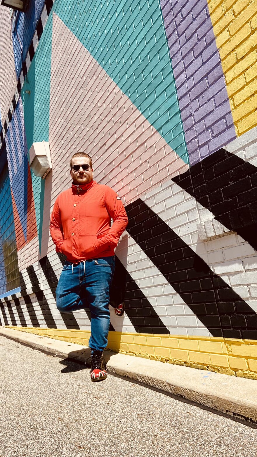 Guy Snowdon standing for a portrait against an outside mural