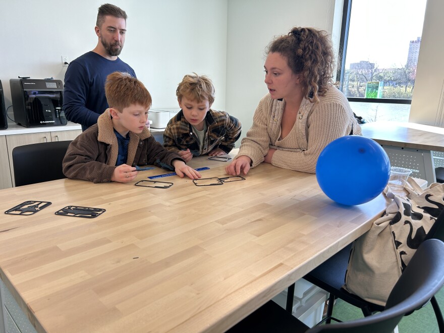 Inside the Makerspace at the Bledsoe-Miller STEAM Center, Henry, Julian and mom Rachel build 3D printed model airplanes. The Makerspace also includes miniature microscopes and sewing machines for hands-on learning.