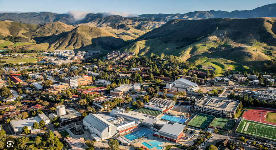 An aerial view of a college campus surrounded by green mountains.