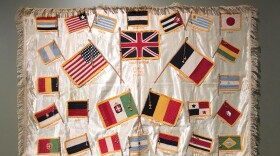 A silk throw or table cover with embroidered and appliqued flags of the Allied Nations from the WWI Museum and Memorial's collection.
