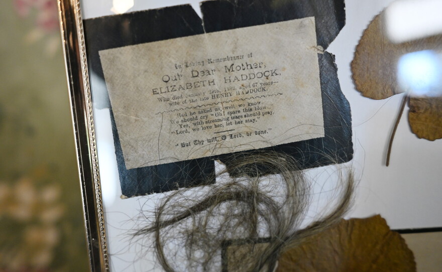 Frame holding leaves, a prayer card and lock of hair