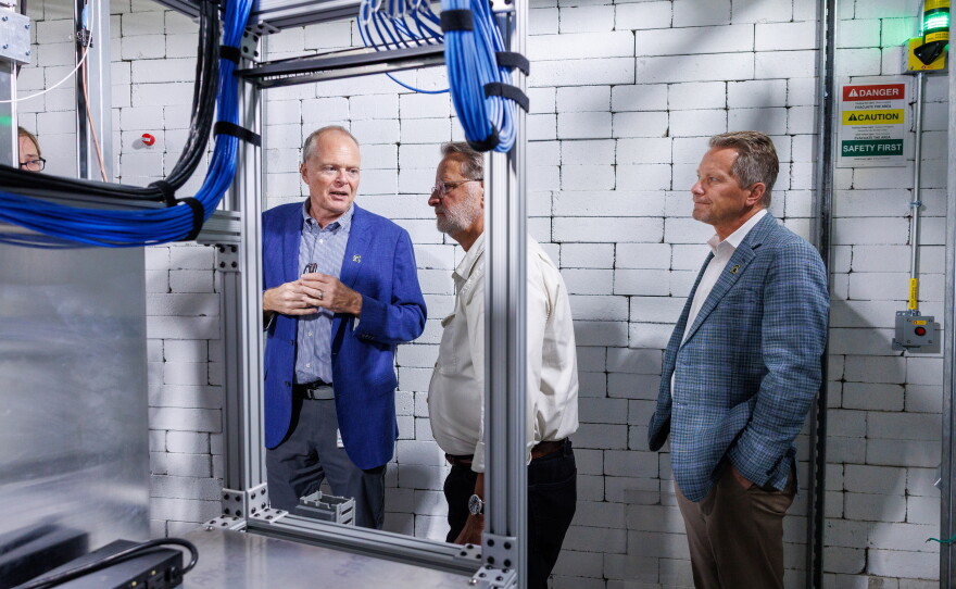 U.S. Sen. Gary Peters, center, visits the Facility for Rare Isotope Beams in East Lansing, Mich., on Aug. 28, 2026. He is joined on the tour by Michigan State University President Kevin Guskiewicz, right, and FRIB Laboratory Director Thomas Glasmacher, left. The visit was the last stop on Peters' final motorcycle tour of Michigan as senator.