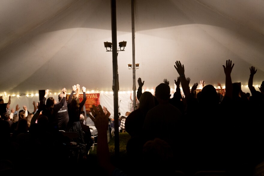 People lift their hands in praise of God at a tent revival in Oneida, Tenn. on Monday, Sept. 22, 2025. The revival was organized by local pastors who feel their community’s faith has faltered in recent years.