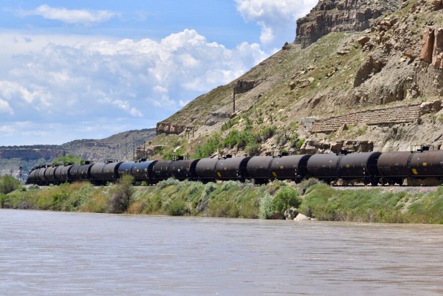 A train of tanker cars travels the tracks along the Colorado River near Cameo