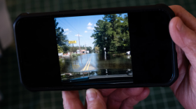 Phyllis Ellis, the owner of Johnny's Drive-In, holds a picture on Nov. 29, 2023, of the floods in downtown Fair Bluff after the hurricane in 2018. (Courtesy - Cornell Watson for WUNC)