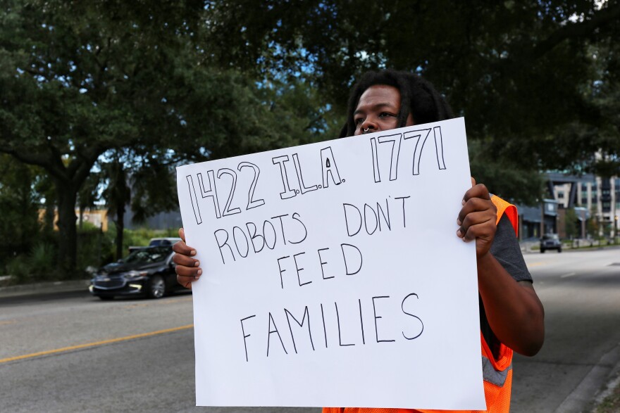 Striking dockworker in Charleston held up a sign that expressed his concern about automation eliminating jobs at ports. Oct. 3, 2024