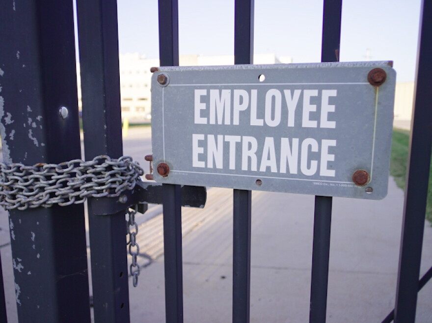 A sign that says "employee entrance" is located on the gates of a factory.