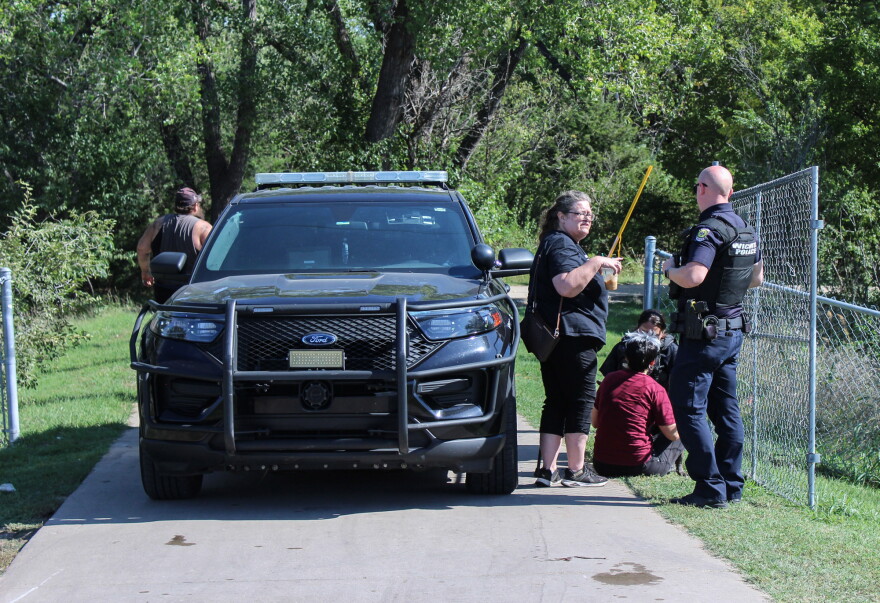 Local community advocate AlmaAnn Klaassen-Jones (center) talks to a police officer at the entrance of Chapin Park on Monday morning. Multiple volunteers and groups were allowed to help finish moving people out of the park.