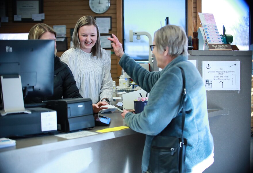 A customer waves to employees at Rockers Pharmacy after picking up a prescription.  