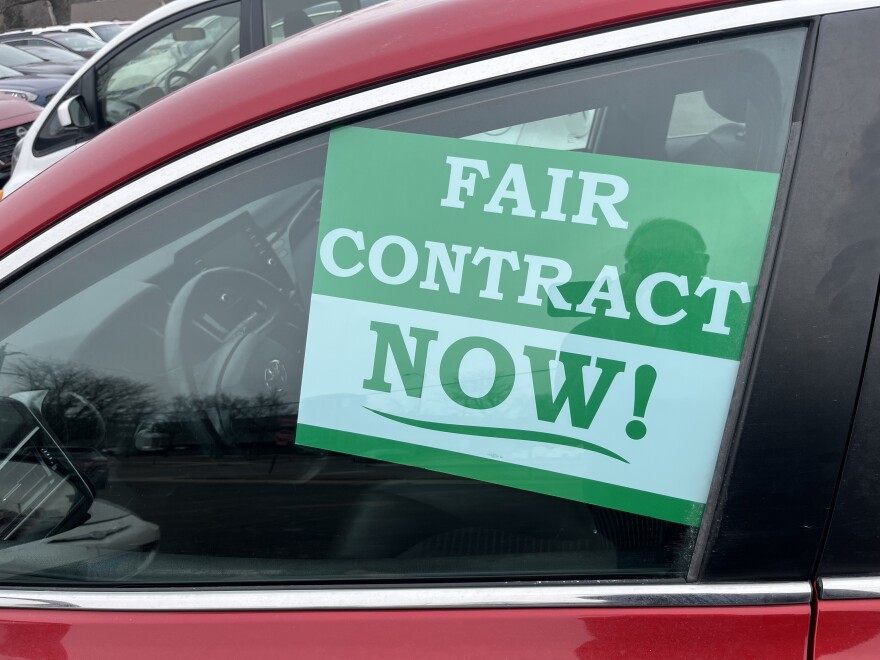 A picture of a car with a "Fair Contract Now" sign in the window.